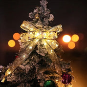 KerstLume als verlichte strik boven in de kerstboom