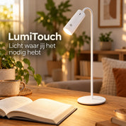 Witte LumiTouch leeslamp op een houten bureau naast een boek